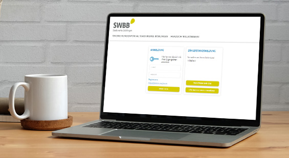 Digitales Kundenportal der SWBB: Bild eines Laptops neben einer weißen Tasse auf einem Holzschreibtisch. Auf dem Bildschirm ist das Kundenportal der SWBB Website geöffnet.
